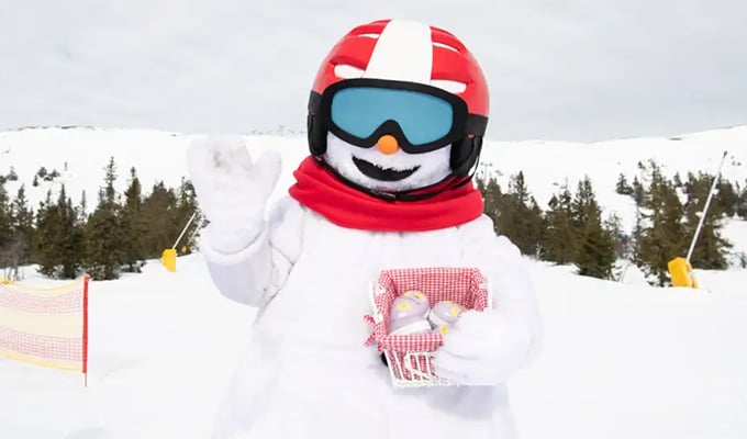 Maskoten snømannen Valle holder i en kurv med påskeegg