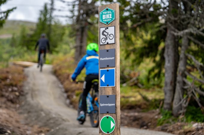Gutt på sykkel foran et skilt som viser til stiene Humlesnurr og Spirrevippen
