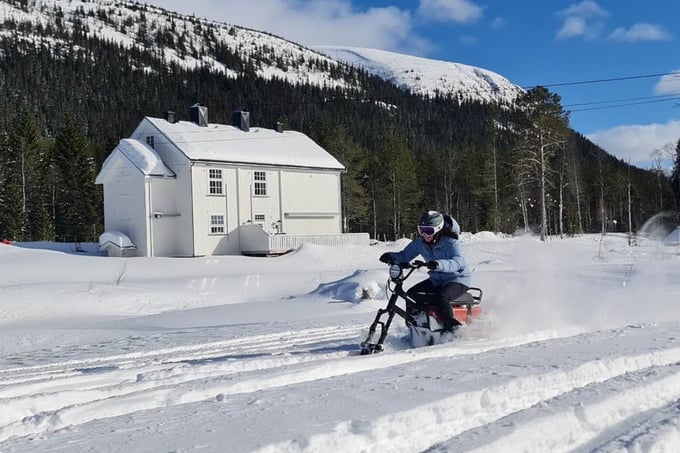 Lady riding a moonbike in a winter landscape with Villa Fregn in the background